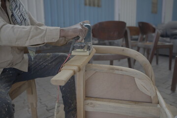 Carpenters use a sander to sand the surface of the wood to smooth the woodwork before painting, man of carpenter working with machine on chair stock images raw image