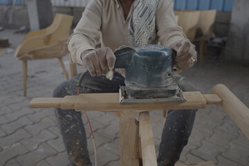 Carpenters use a sander to sand the surface of the wood to smooth the woodwork before painting, man of carpenter working with machine on chair stock images raw image