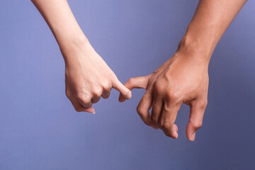 Two people holding hands. Young love couple pinky promise or pinky swear.  - obrazy, fototapety, plakaty