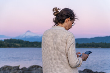Naklejka premium Woman chatting on a smartphone outdoors.