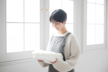 窓際で洗濯物を持つ女性