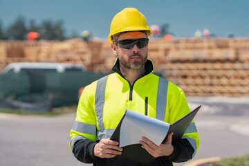Fototapeta premium Professional construction worker in new house. Portrait of worker man outdoor. Construction worker with hardhat helmet on construction site. Engineer worker in builder uniform.