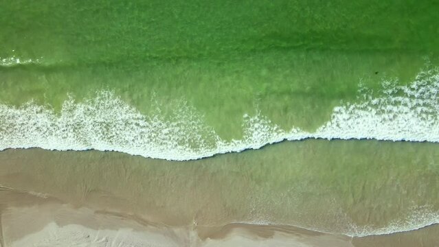 Top down aerial trucking above gentle waves running onto pristine beach, Weskus