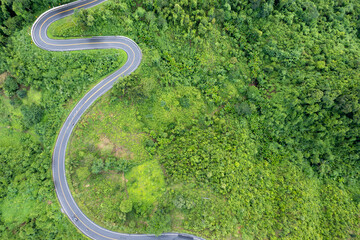 Top view Landscape of Morning Mist with Mountain Layer at north of Thailand. view of countryside road passing through the green forrest and mountaintain ridge and clouds in rural jungle bush forest