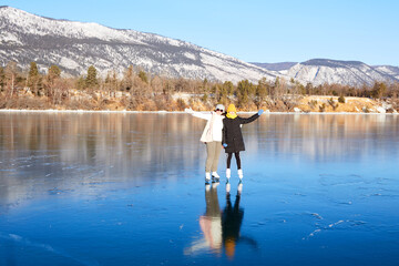 Mom and daughter are skating on the frozen Lake Baikal. Transparent ice. Winter travel, active family holidays, sports.