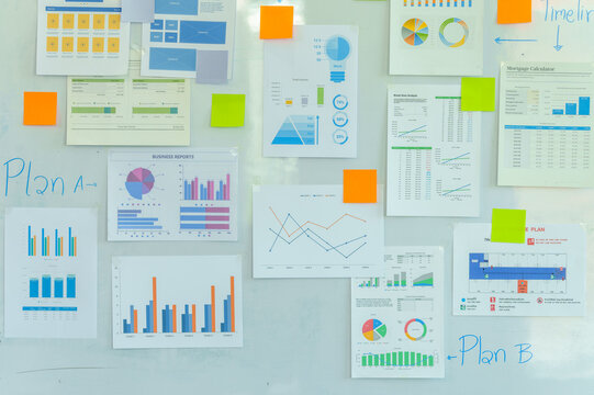wall with various colorful business charts, graphs, and sticky notes, indicating planning or brainstorming activities.