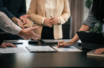 diverse group of Asian professionals, including middle-aged and mature individuals, gathered around a table in a business setting, discussing documents with focused attention.