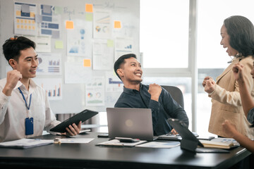 diverse group of Asian professionals, including middle-aged and mature individuals, gathered around a table in a business setting, discussing documents with focused attention.