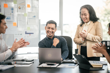 diverse group of Asian professionals, including middle-aged and mature individuals, gathered around a table in a business setting, discussing documents with focused attention.