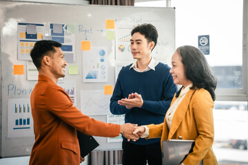 Asian middle-age man and mature woman professionals engaged in boardroom meeting. presents data from clipboard to his colleagues, suggesting annual review or planning session.