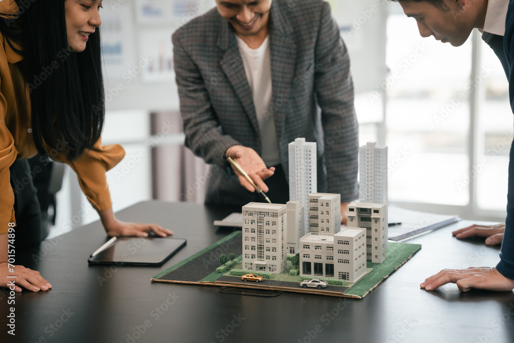 Wall mural asian team is engaged in a lively discussion over a scale model of a cityscape, likely representing 