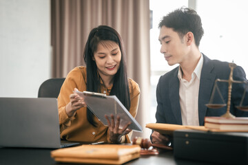 Asian man and woman collaborating professional setting, law office. reviewing documents on tablet,...