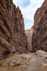 A shallow  stream flows between high mountains at beginning of the route along the Wadi Numeira hiking trail in Jordan