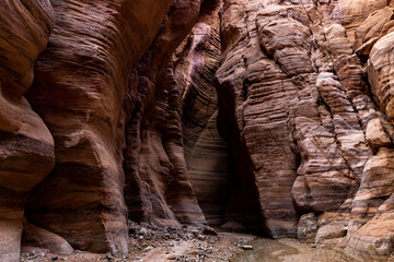 A shallow  stream flows between rocks painted with beautiful natural patterns along walking trail in Wadi Numeira gorge in Jordan