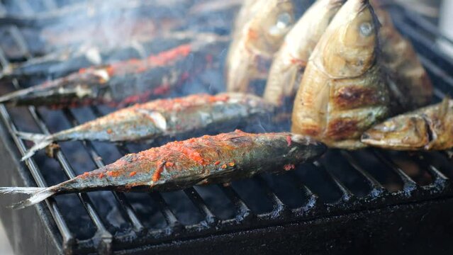 Close-up shot of cooking fish. Baking and roasting marinated fish on barbecue grill. Sea bass or grouper grilled over charcoal. 4K	