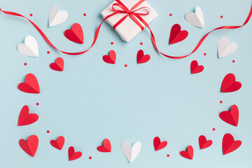 Valentine or mother day festive composition with gift or present box and red hearts on pastel blue...