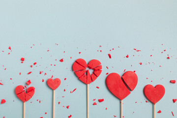 Valentine day concept with broken red lollipop hearts on pastel blue background top view. Flat lay...