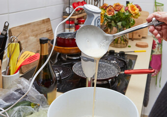 Homemade Kitchen Hostess Pouring Pancake Mix from Ladle into Leaking Bowl