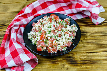 Salad with tomatoes, cottage cheese, dill and olive oil on a wooden table