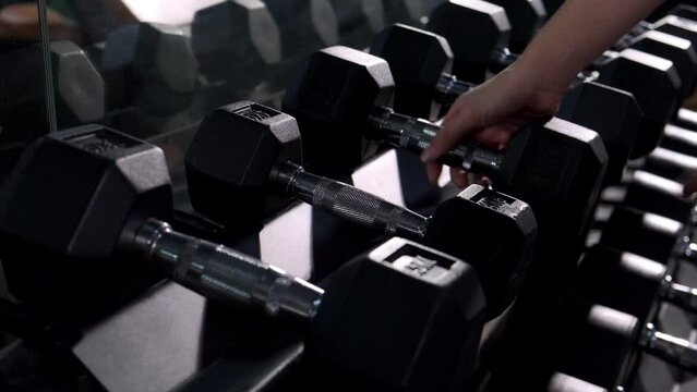 gym interior, close up hand put metal dumbbells and fit life.
