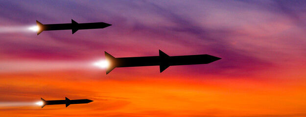 Fired missiles fly to the target. Missiles at the sky at sunset. Missile defense. Rockets attack concept.