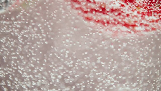 A macro video showing blueberries and strawberries splashing in seltzer water.