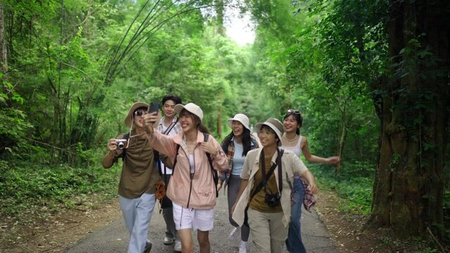 4K Group of Young Asian man and woman friends travel nature on summer holiday vacation. Happy people enjoy and fun outdoor lifestyle using digital camera taking picture together at forest mountain.