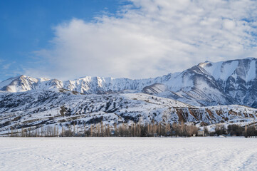winter landscape with the Tien Shan mountains in Kazakhstan in snow under a blue sky with clouds