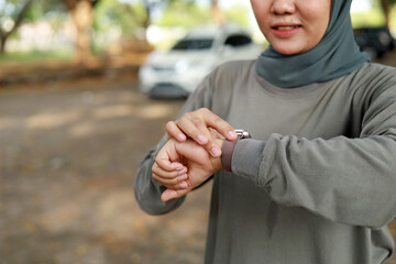 Close up photo of young muslim woman with scarf setting smart watch before jogging in the morning