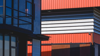Geometric lines pattern background in street minimal style. Aluminium louver of orange metal warehouse near modern office industrial building with sunlight and shadow on surface, perspective side view