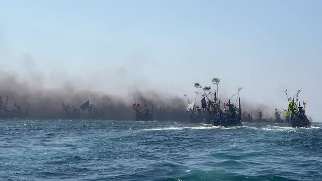 Fishing boats in Indian Ocean during Patik Laut festival in Muncar, Banyuwangi, Jawa, Indonesia covered in smoke exhaust