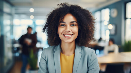 Portrait of young confidant business woman standing in the office smiling, co-workers and employees in the background - Powered by Adobe