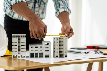 Close up Asian individual architect or engineer holding building scale model of multi-story...