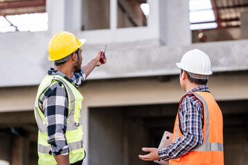 Asian people, two man, holding blueprints Structural engineers examine structural plans for office buildings and housing developments on-site, discussing work at construction site.