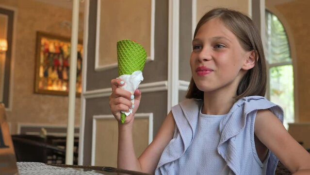 Little girl eating ice cream in restaurant. 4k video footage in slow motion