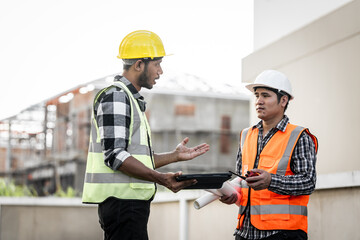 Asian people, two man, holding blueprints Structural engineers examine structural plans for office buildings and housing developments on-site, discussing work at construction site.