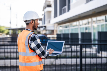 engineer in a high-visibility vest and hard hat, intently reviewing a document or blueprint, with a modern building in the background.