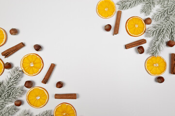 Christmas composition, dried orange slices, fir tree branches, cinnamon sticks, hazelnuts on white background. Christmas, New Year, winter concept. Top view, flat lay, copy space.
