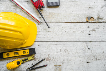Top view construction tools such as a yellow hard hat, spirit level, measuring tape, folding ruler...