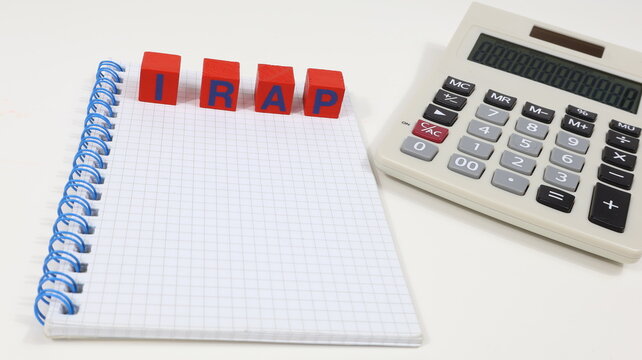 Single word "IRAP" on wooden block, taxes isolated, with an office desk background.