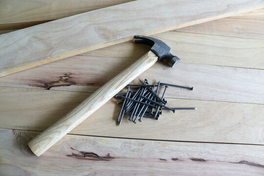 Hammer and nails pile isolated on a wooden background.