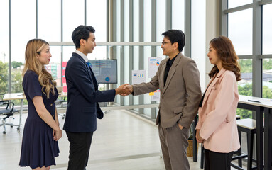 Obraz premium Corporate professional in formal attire engaged in a handshake during a meeting in a well-lit office space.