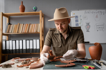 Male archaeologist or digger working in the office studying finds from excavations