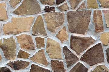 Stone wall with different colored stones. Texture, various natural stones