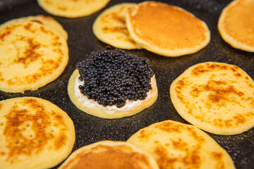 Blinis with black caviar and cream cheese, on a festive dish, mini pancakes, an elegant appetizer,...