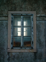 Obraz premium Altes Fenster mit verwittertem Holzrahmen an dunkler Fassade 