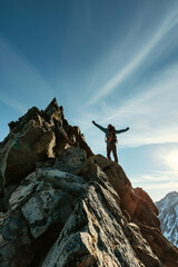 Hiker reaching the summit of a mountain, arms raised in triumph.