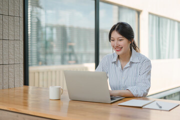 Happy beautiful Asian woman working on financial tasks with a business report and calculator. Financial or accounting concept.