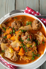 Soup with meatballs cabbage and vegetables on a plate.