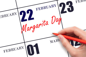 February 22. Hand writing text Margarita Day on calendar date. Save the date.